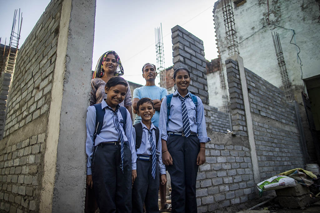 Group portrait of homeowner Rajani and her family in front of their new, under-construction house.
